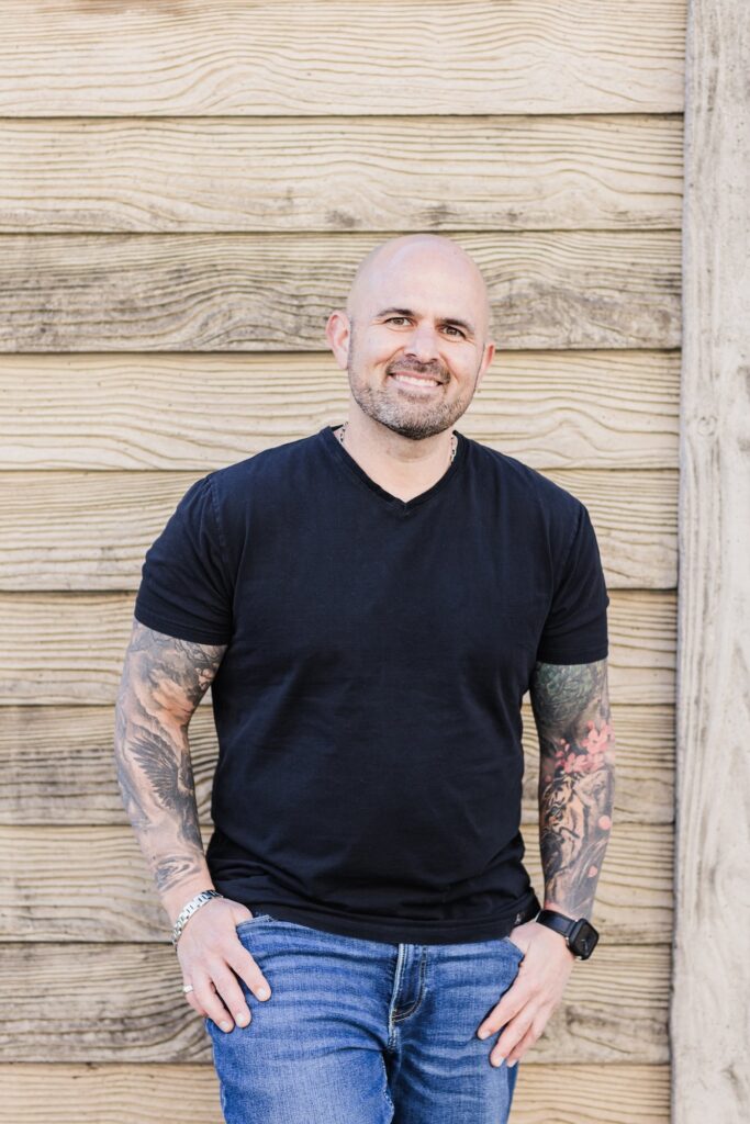 Mike Cinelli standing next to building made of wood